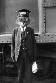 a cat wearing a suit and hat standing in front of a train