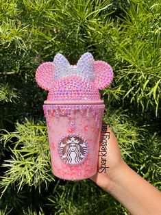 someone is holding up a starbucks cup with minnie mouse ears on it and pink sprinkles