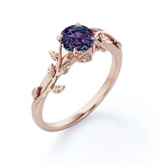 a gold ring with a purple stone in the center and leaves on each side, set against a white background