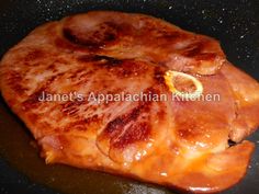 some meat is cooking in a skillet on the stove top with oil and seasoning