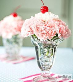 pink carnations and daisies in glass vases with cherries on top