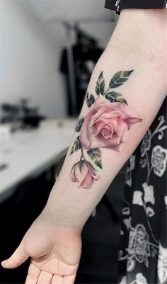 a woman's arm with a pink rose tattoo on the left side of her arm