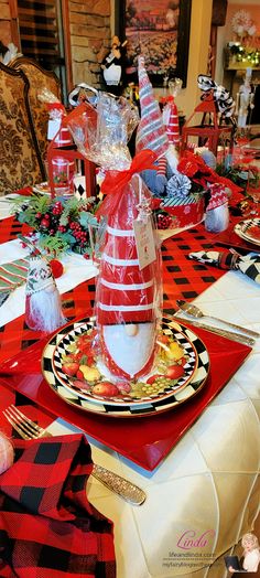 the table is set with red and black place mats, plaid napkins, silverware, and candy canes