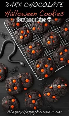 chocolate halloween cookies on a cooling rack with orange candies in the middle and black background