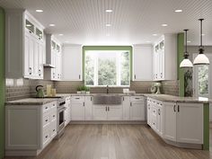 a large kitchen with white cabinets and green trim on the walls, wood flooring