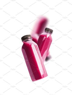 three pink smoothies in glass bottles on a white background