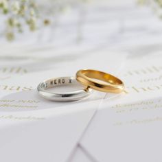 two gold and silver wedding rings sitting on top of each other