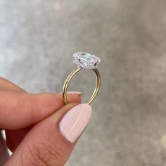 a woman's hand holding an engagement ring with a diamond on the top and bottom