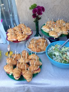 sandwiches and salads on plates with toothpicks sticking out of them sitting on a table