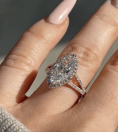 a woman's hand with a diamond ring on top of her finger and an oval shaped diamond in the middle