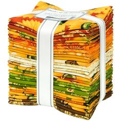 a stack of colorful fabric with a white ribbon around it's end and an orange, yellow, green, and brown design on top