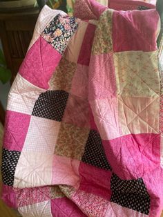 a pink and black quilt sitting on top of a chair