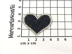 a black and white heart brooch sitting on top of a ruler