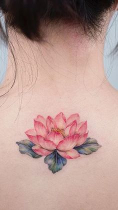 a woman's back with a pink flower tattoo on it