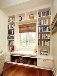 a window seat in front of a book shelf filled with books