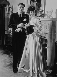 an old black and white photo of a man and woman in formal wear standing next to each other