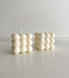 two white candles sitting next to each other