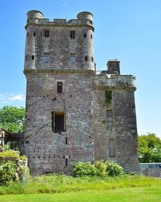 an old stone castle sitting on top of a lush green field