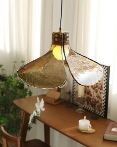 a table with a lamp hanging from it's side next to a chair and potted plant