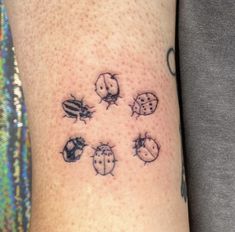 a ladybug tattoo on the left arm with six ladybugs all over it