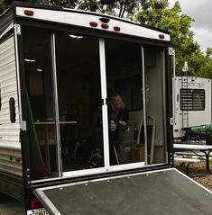 a woman sitting in the back of a trailer next to a table with chairs on it