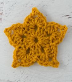 a yellow crochet star ornament sitting on top of a white table