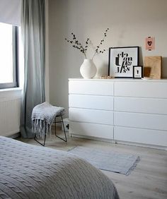 a white dresser sitting next to a window filled with pictures and vase on top of it