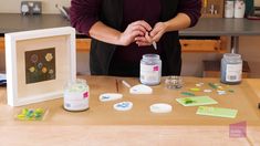 a woman standing in front of a table with some crafting supplies on top of it