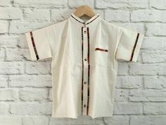 Boy's Traditional Handmade Mexican Guayabera Shirt - Beige - Off White Handmade in Chiapas, Mexico The embroidery pattern & embroidery colors will vary due to the handmade nature of the shirt. If you have any questions or requests please send us a message. Size 2 Measurements (approximate): Length: 12.5 - 13.5 inches Armpit to armpit: 10 - 10.5 inches Size 4 Measurements (approximate): Length: 13.5 - 14 inches Armpit to armpit: 11.5 - 12.5 inches Size 6 Measurements (approximate): Length: 15 - 1 Traditional Cotton Top With Stand Collar, Traditional Beige Short Sleeve Tops, Traditional White Short Sleeve Sets, Traditional Cotton Shirt With Buttons, White Cotton Tops With Traditional Patterns, Traditional White Sets With Stand Collar, White Cotton Top With Traditional Patterns, Traditional Summer Shirt With Camp Collar, Traditional Short Sleeve Summer Kurta