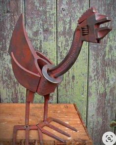 a metal bird sculpture sitting on top of a wooden box