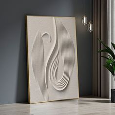 a white and gold framed art piece sitting on top of a hard wood floor next to a potted plant