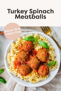 a white bowl filled with pasta and meatballs on top of a table next to a fork