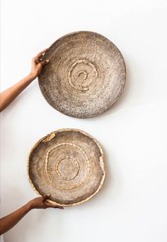 two baskets being held up by hands on a white surface with one holding the other