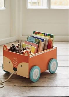 a wooden toy cart filled with books on top of a hard wood floor next to a window