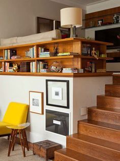 a living room filled with furniture and bookshelves next to a stair case full of books