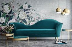 an elegant living room with floral wallpaper and blue couches, gold side tables