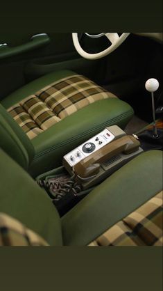 a remote control sitting on top of a green seat in a car with plaid upholstered seats