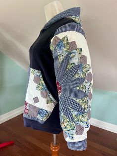 a blue and white jacket with flowers on it sitting on top of a wooden stand