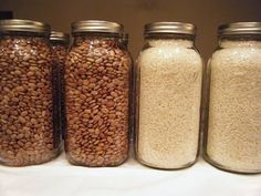 four jars filled with different types of grains