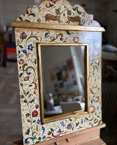 an ornately decorated mirror sitting on top of a wooden table