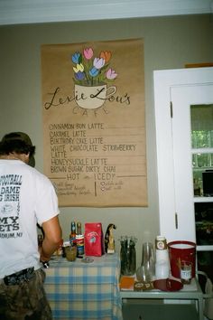 a person standing in front of a table with food on it and a sign hanging above the table