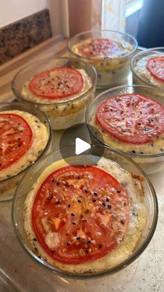 six small pizzas in glass dishes on a counter with tomatoes and black pepper sprinkles