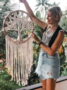 a woman holding up a white dream catcher