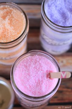 three jars filled with different colored powders on top of a wooden table next to each other