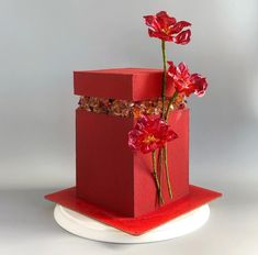 a red box with flowers in it sitting on a plate