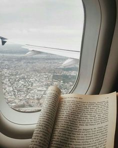 an open book sitting on top of an airplane window