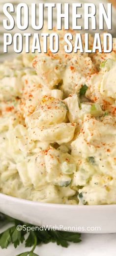 a white bowl filled with potato salad and garnished with parsley on the side