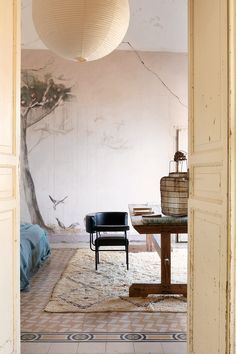 an open door leading to a room with a tree mural on the wall and chairs