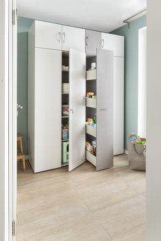 an open door shows the inside of a room with white cupboards and shelving