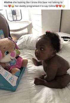 a baby sitting on a bed next to a stuffed animal